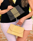 Model wearing Wynwood Natural Straw Handbag with Metallic Detailing & Horn Handle handmade loomed raffia in natural straw color and silver metallic vegan leather in three vertical bands of color with the metallic weave centered on the purse under the handles and the same bag in Black - Shebobo