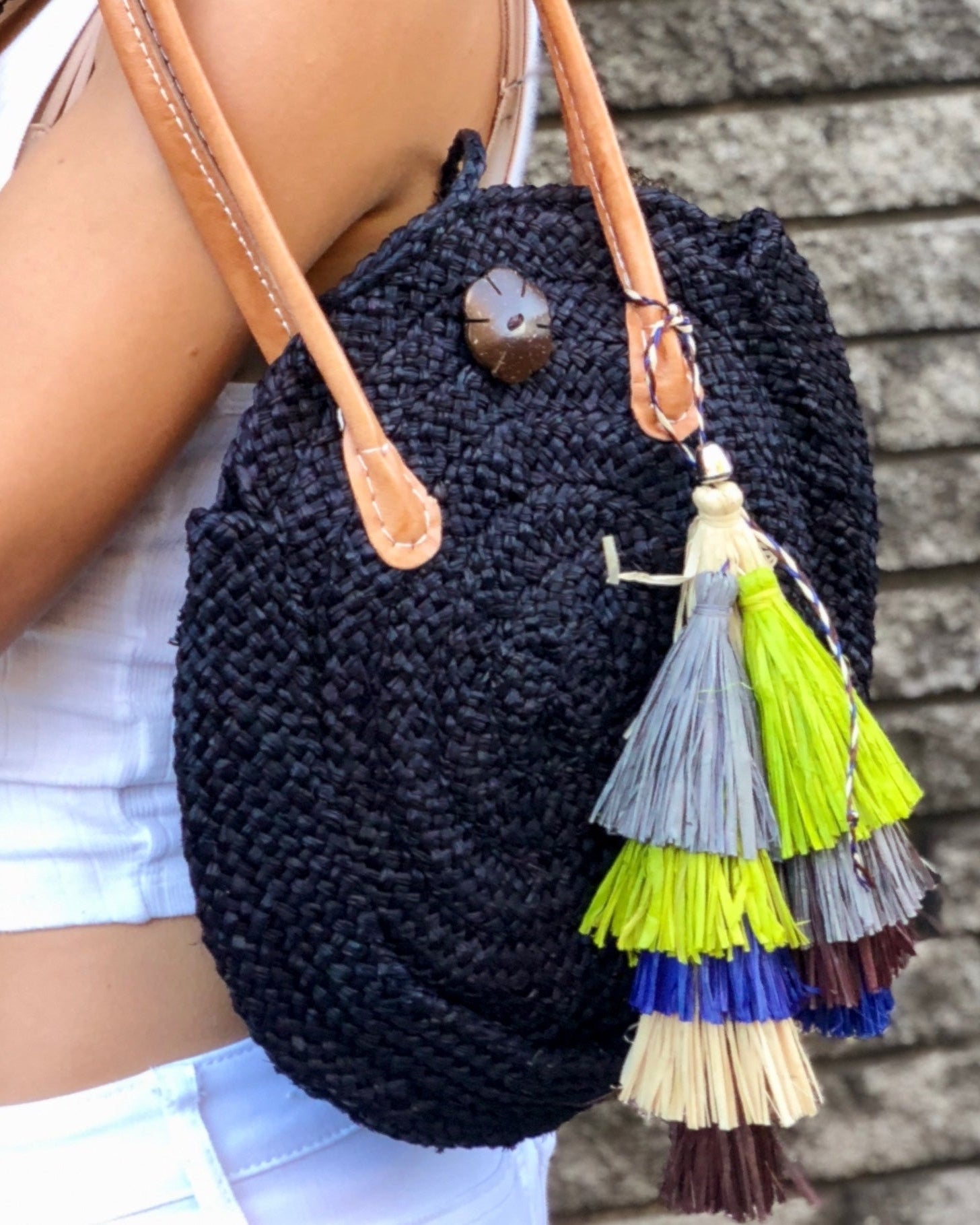 Model wearing Tassels Layered Raffia Tufts Charm Embellishment Yerba Multicolor handmade knotted and brushed natural raffia palm fiber in a multicolor layered tuft tassel of natural straw color, lime green, grey, chocolate dark/brown, and dusk navy/dark/blue beach bag handbag charm embellishment or party decor - Shebobo