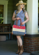 Model wearing Zafran 3 Tone Color Block Beach Straw Bag with Plastic Liner handmade loomed raffia palm fiber in three equally sized horizontal bands of red, natural straw color, and grey with wood button and leather handles - Shebobo (with Macho Unisex Straw Cowboy Hats with Adjustable Wire Edge)