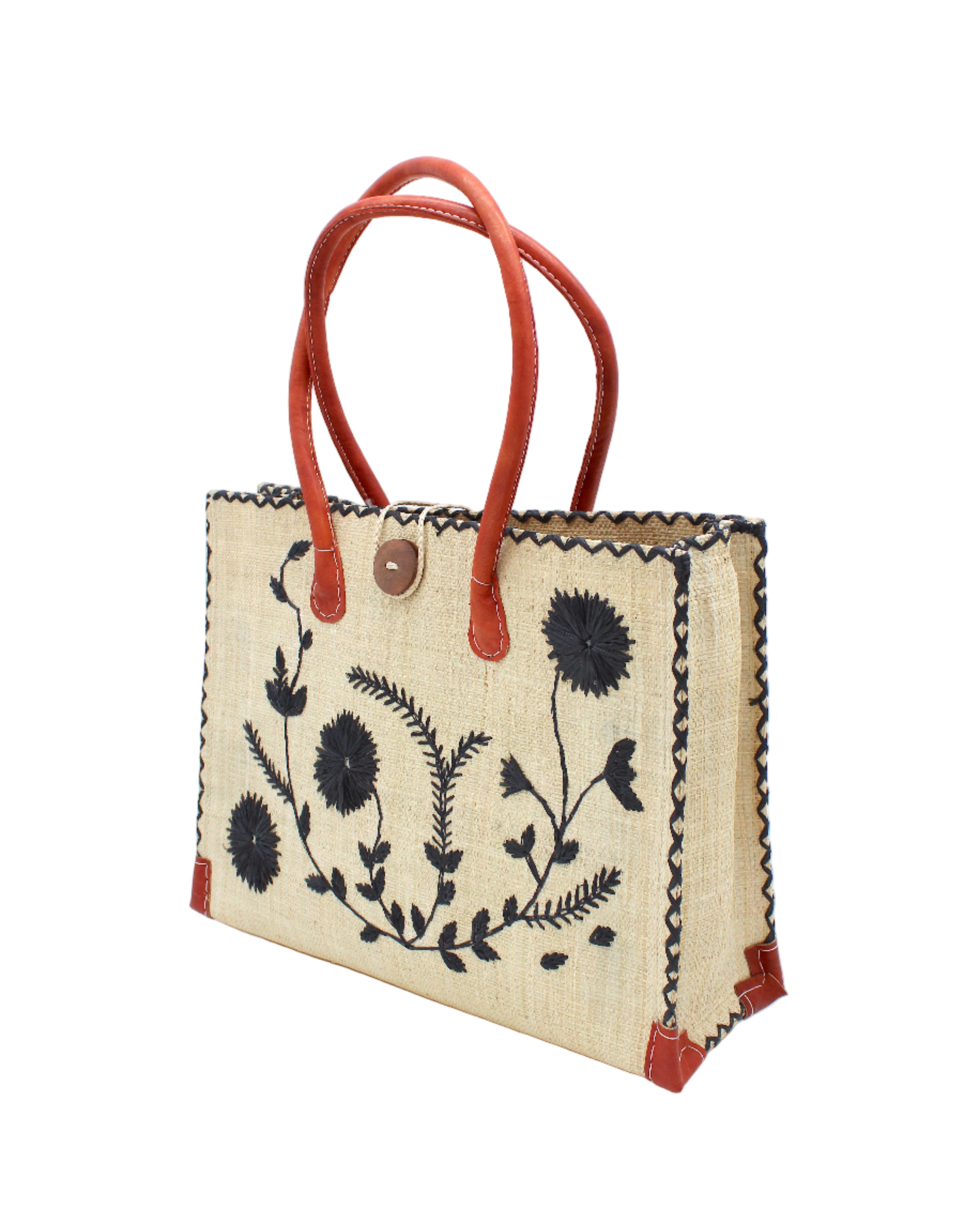 Side view Zafran Natural & Black Embroidered Straw Beach Bag with Floral Pattern handmade natural raffia palm fiber in a solid hue of natural straw color with asymmetrical floral leaf, vine, and flower pattern in black with matching cross-stitch edging, leather handles, and wooden button closure shoulder bag handbag tote - Shebobo