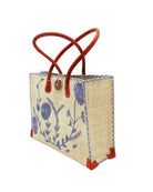 Side view Zafran Natural & Denim Embroidered Straw Beach Bag with Floral Pattern handmade natural raffia palm fiber in a solid hue of natural straw color with asymmetrical floral leaf, vine, and flower pattern in denim retro/light/blue with matching cross-stitch edging, leather handles, and wooden button closure shoulder bag handbag tote - Shebobo