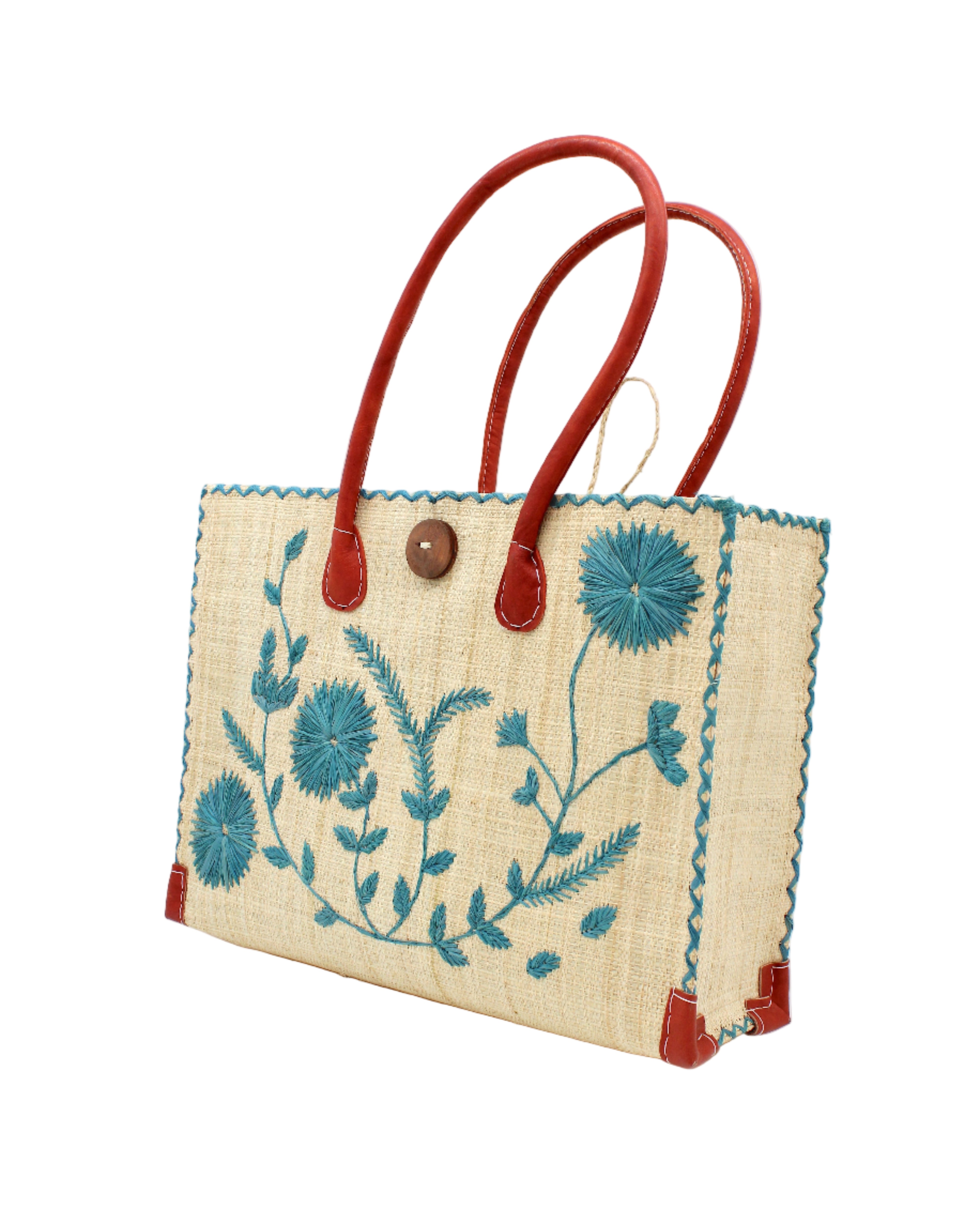 Side view Zafran Natural & Turquoise Embroidered Straw Beach Bag with Floral Pattern handmade natural raffia palm fiber in a solid hue of natural straw color with asymmetrical floral leaf, vine, and flower pattern in turquoise blue/green with matching cross-stitch edging, leather handles, and wooden button closure shoulder bag handbag tote - Shebobo