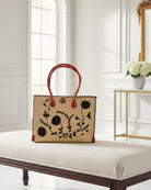 Zafran Natural & Black Embroidered Straw Beach Bag with Floral Pattern handmade natural raffia palm fiber in a solid hue of natural straw color with asymmetrical floral leaf, vine, and flower pattern in black with matching cross-stitch edging, leather handles, and wooden button closure shoulder bag handbag tote - Shebobo
