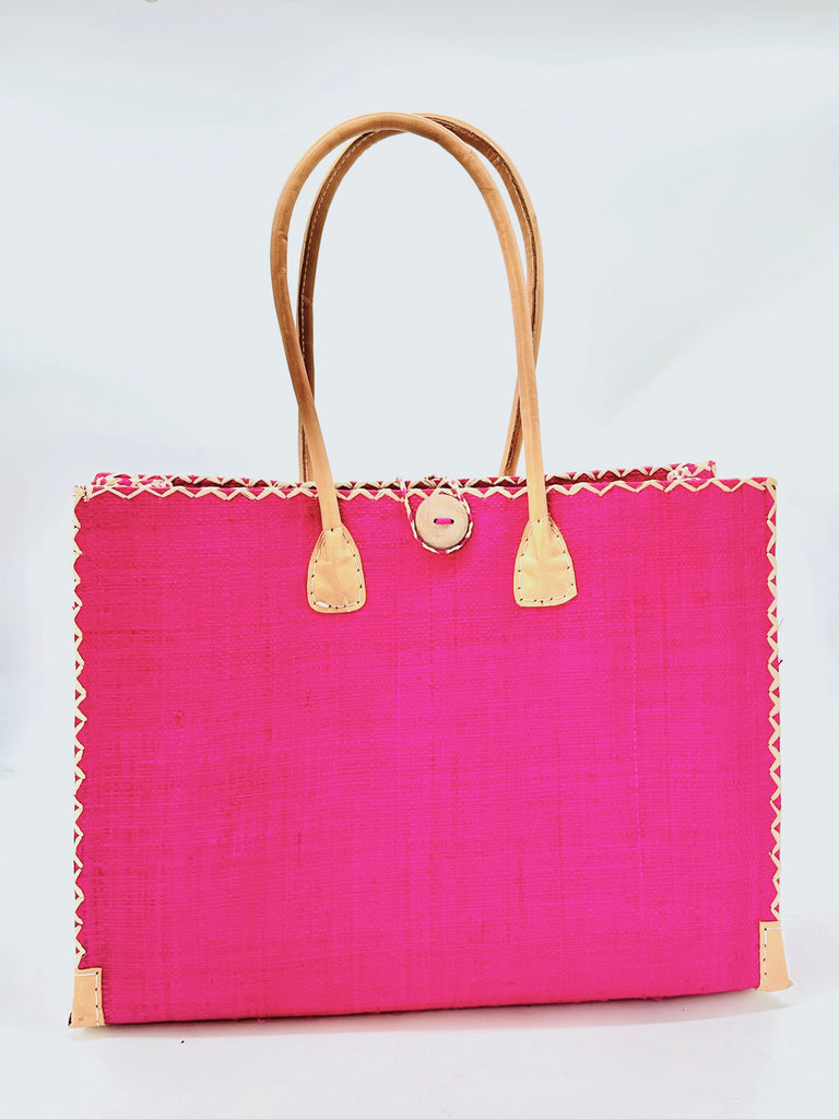 Zafran Large Straw Beach Bag with Plastic Liner handmade loomed raffia in Fuchsia Pink with contrasting cross stitch edge binding, wood button closure, and leather handles & feet plus assorted print plastic lining - Shebobo