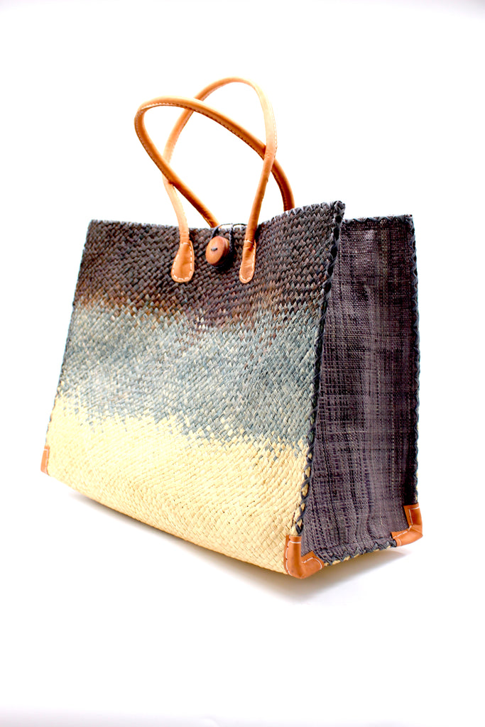 Side View Holden Black Ombre Zafran Large Straw Beach Bags handmade dip dyed raffia woven into a three part horizontal ombre pattern of black on the top, grey in the middle and both sides, and natural on the bottom with cross stitch edging, wooden button, and leather handles - Shebobo