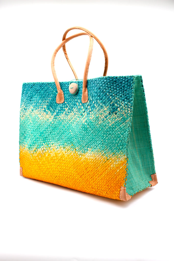 Side view Holden Turquoise Ombre Zafran Large Straw Beach Bags handmade dip dyed raffia woven into a three part horizontal ombre pattern of turquoise blue on the top, seafoam blue/green in the middle and both sides, and saffron yellow on the bottom with cross stitch edging, wooden button, and leather handles - Shebobo