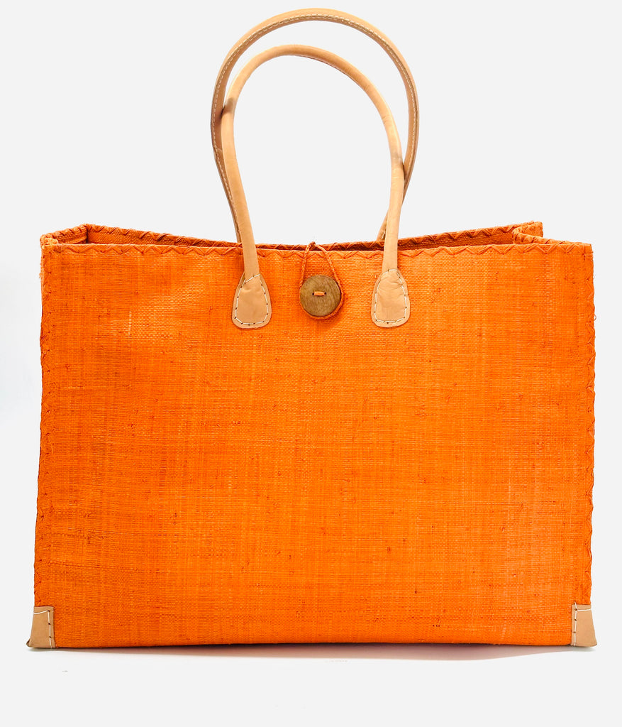 Zafran Large Straw Beach Bag with Plastic Liner handmade loomed raffia in coral orange/red with contrasting cross stitch edge binding, wood button closure, and leather handles & feet plus assorted print plastic lining - Shebobo