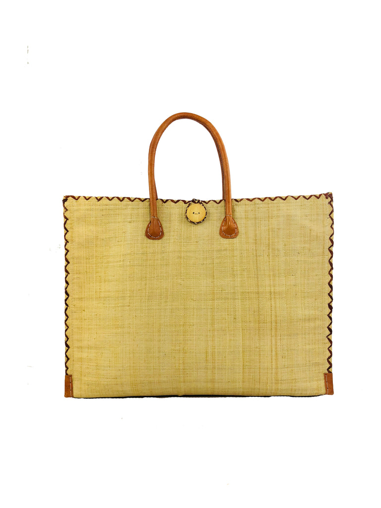 Zafran Large Straw Beach Bag with Plastic Liner handmade loomed raffia in natural straw color with contrasting cross stitch edge binding, wood button closure, and leather handles & feet plus assorted print plastic lining - Shebobo