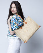Model wearing Zafran Natural Embroidered Straw Beach Bag with Floral Pattern handmade natural raffia palm fiber in a solid hue of natural straw color with asymmetrical floral leaf, vine, and flower pattern in Natural with matching cross-stitch edging, leather handles, and wooden button closure shoulder bag handbag tote - Shebobo