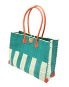 Side view Zafran Two Tone Wide Stripe Teal and Natural Straw Beach Bag handmade loomed raffia palm fiber in a solid hue of teal dark/blue/green on the top half of the bag and a two tone even width vertical wide stripe pattern of teal and natural straw color on the bottom half of the bag with leather handles and feet and matching crosshatch stitch edging shoulder bag - Shebobo