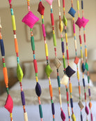 Zola Garland Multicolor Raffia Pillow Bead Strands Room Decor Festive beaded strands of handmade loomed raffia pillow beads, hand wrapped long raffia loop beads, and painted plastic beads in bright, bold, fun colors (sold as single strand or pack of 10 Strands) - Shebobo