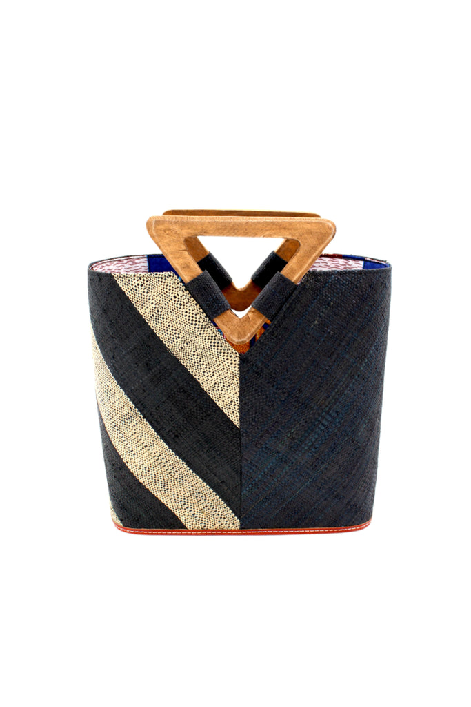 Zuki Two Tone Black Straw Handbag With Wood Triangle Handle handmade loomed raffia palm fiber in a two tone pattern with the left half of the bag even width stripes of black and natural straw color oriented as a diagonal stripe and the right half of the bag a solid hue of black with carved wood handles - Shebobo