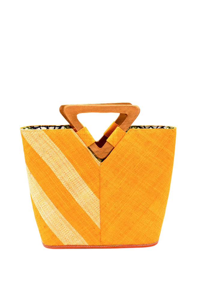 Zuki Two Tone Saffron Straw Handbag With Wood Triangle Handle handmade loomed raffia palm fiber in a two tone pattern with the left half of the bag even width stripes of saffron yellow/orange and natural straw color oriented as a diagonal stripe and the right half of the bag a solid hue of saffron with carved wood handles - Shebobo