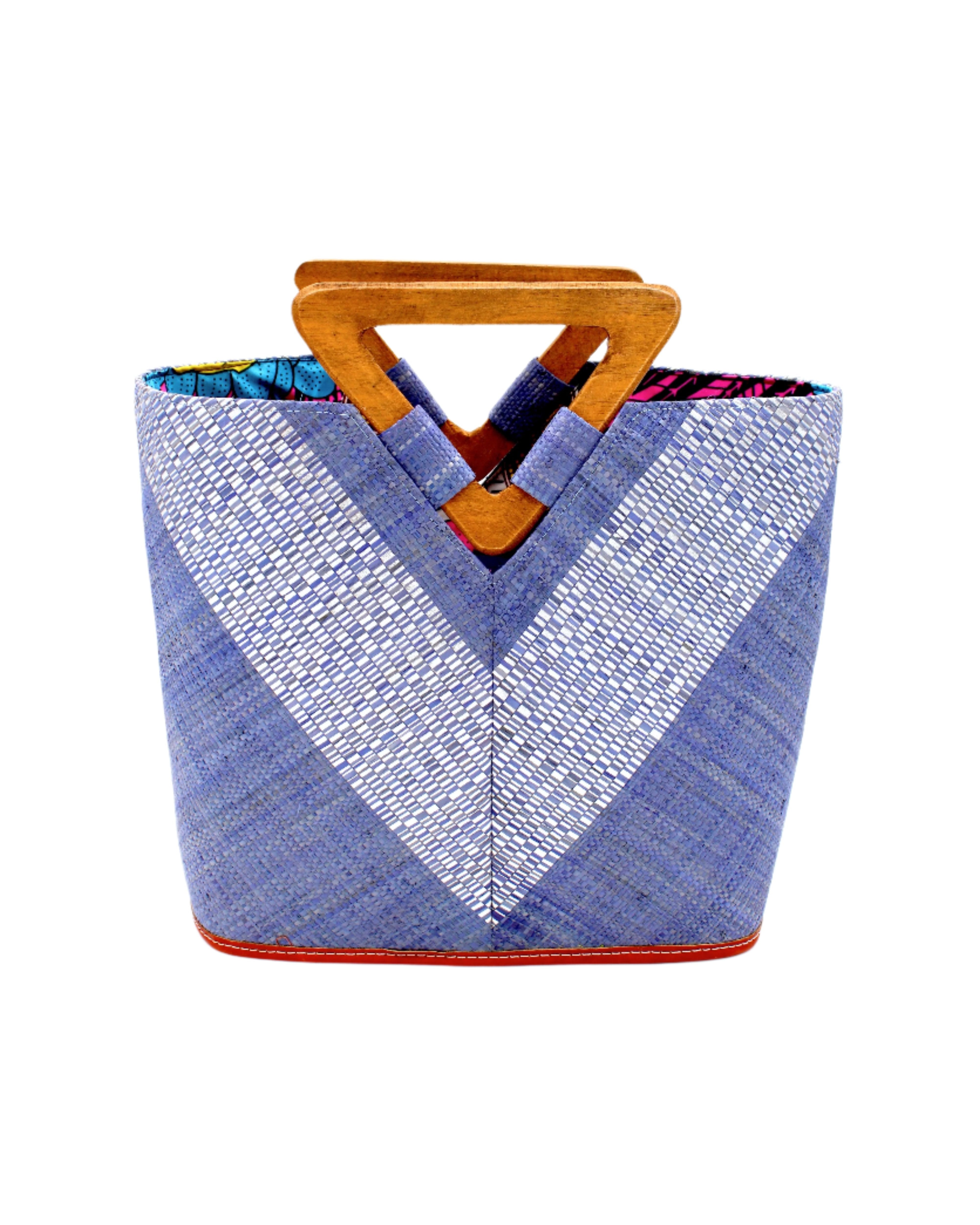 Zuki Wynwood Denim Straw Handbag with Metallic Detailing & Wood Triangle Handle handmade loomed raffia palm fiber in a solid hue of denim retro/light/blue with incorporated vegan leather  silver metallic strands in a V pattern across the front and back of the bag with assorted print African wax cloth liners and carved wooden triangle handle purse - Shebobo