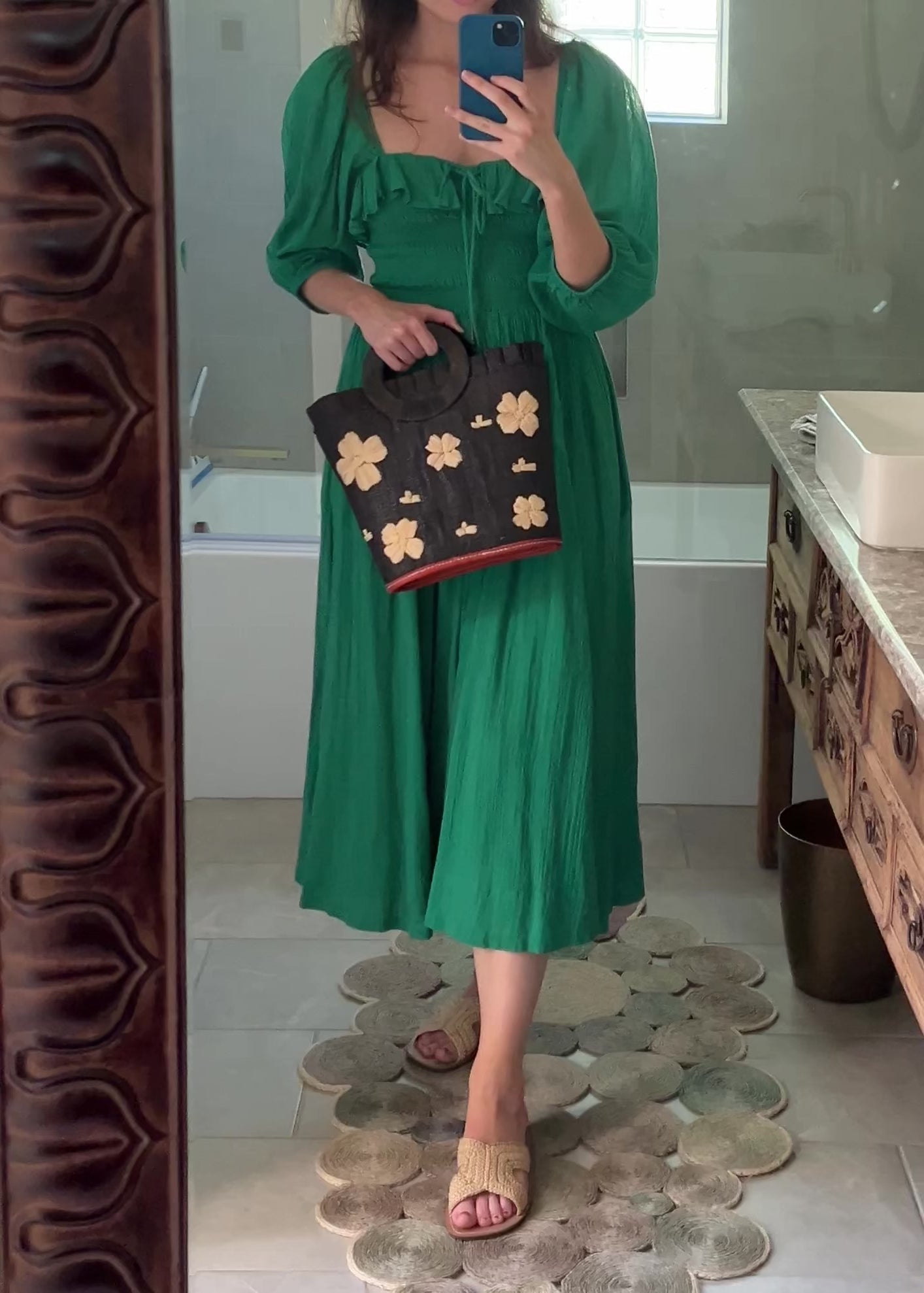 Model wearing Tulum Straw Bucket Bag with Flower Embroidery and Horn Handle Black Purse with Ruffle Edge handmade loomed raffia palm fiber in a solid hue of black with natural straw color hand embroidered floral pattern with multiple sized flowers and raffia ruffle on the opening  handbag - Shebobo