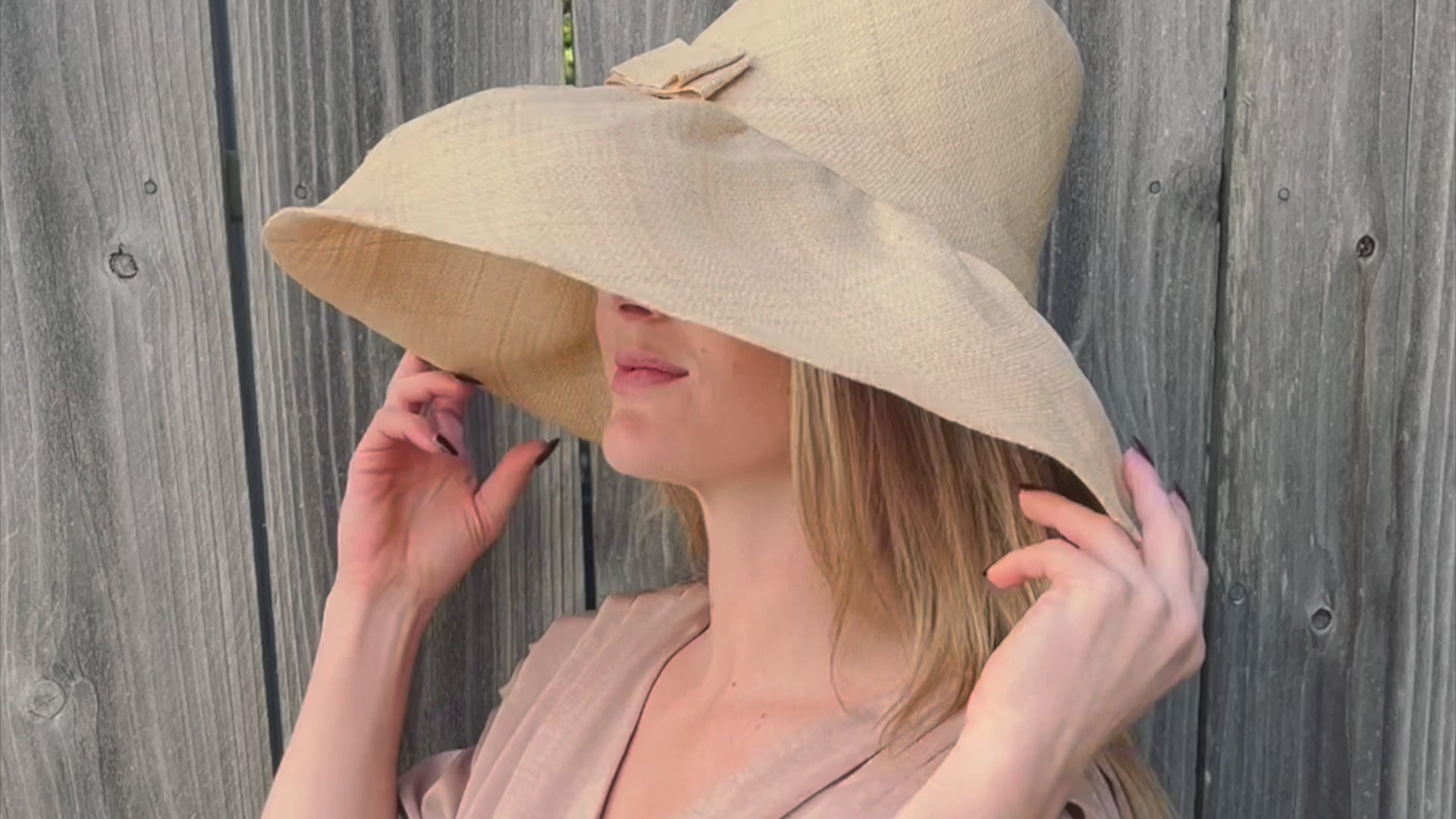 Model wearing Monica 7 inch wide brim packable straw sun hat in natural - handmade loomed raffia palm fiber in a solid hue of natural straw color can be worn may ways to suit your style - Shebobo