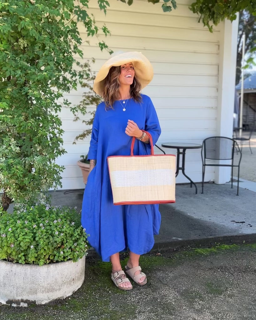 Model wearing Wynwood Natural Straw Basket Bag Handbag with Metallic Detailing handmade loomed raffia in natural straw color and silver metallic vegan leather in three evenly sized horizontal bands of color with the metallic weave centered on the purse with leather binding and handles - Shebobo (with Audrey 5" & 7" Wide Brim Big Bow Solid Color Packable Straw Sun Hats)