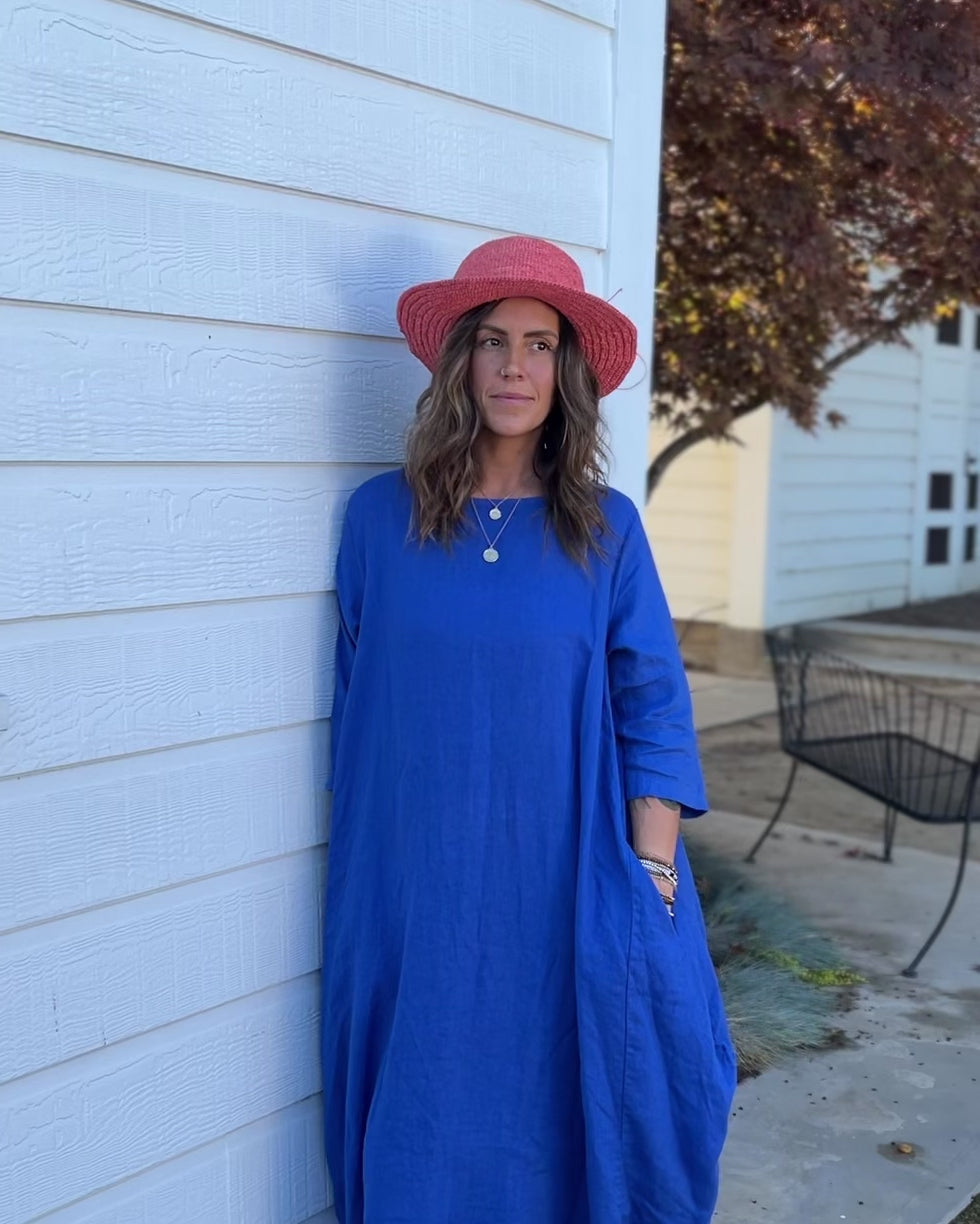 Model wearing 3" Brim Bolero Crochet Straw Sun Hats handmade crochet natural raffia palm fiber in a solid hue of Cherry Blossom pink/orange making a concentric pattern from the center top of the flattened crown spiraling out to the edge of the brim with matching adjustable raffia braid hat band - Shebobo