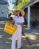 Model wearing Havana Sisal Basket Bag with Tassel Charm Embellishment handmade sisal fiber woven into horizontal wide bands of saffron yellow with two evenly spaced narrow bands of natural straw color create a stripe pattern with natural crochet starfish charm embellishment and leather handles handbag shoulder bag - Shebobo (with Natasha 7" Wide Brim Woven XL Straw Sun Hats)