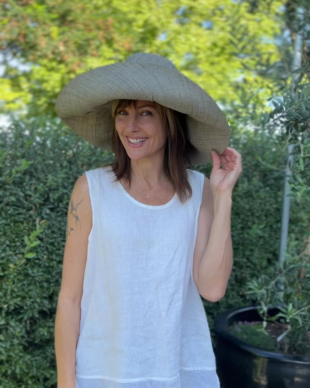 Model wearing Monica 7" Wide Brim Pewter Packable Straw Sun Hat handmade loomed raffia in a solid hue of light grey lightweight malleable flexible sun protection hat - Shebobo