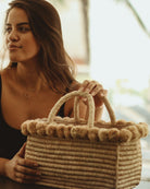 Model wearing Model wearing Rico natural raffia palm fiber hand crochet loop technique cute rectangle shape straw basket handbag with top edge of pompoms purse braided handle bag - shebobo