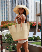 Model wearing Santa Cruz Two Tone Large Straw Tote Bag handmade beach bag loomed raffia solid natural bottom with natural and black vertical pinstripe pattern top plus leather handles xl handbag - Shebobo